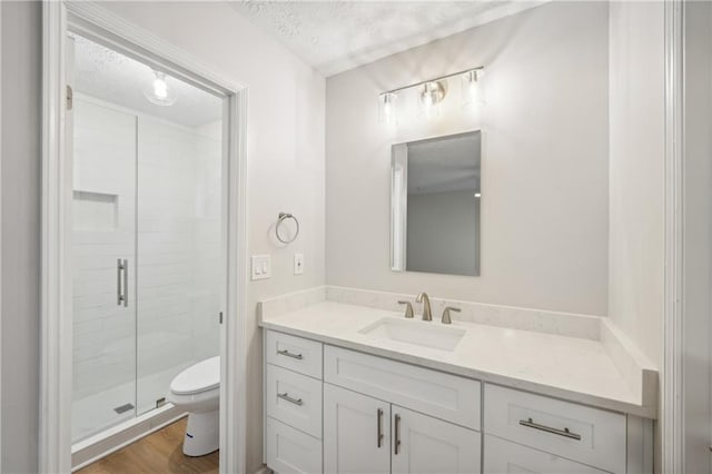 bathroom featuring a textured ceiling, toilet, walk in shower, vanity, and hardwood / wood-style flooring