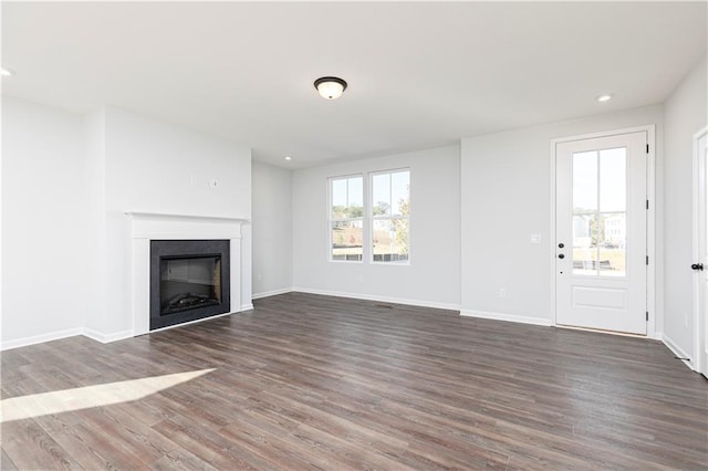 unfurnished living room with dark wood-style flooring, recessed lighting, a fireplace, and baseboards