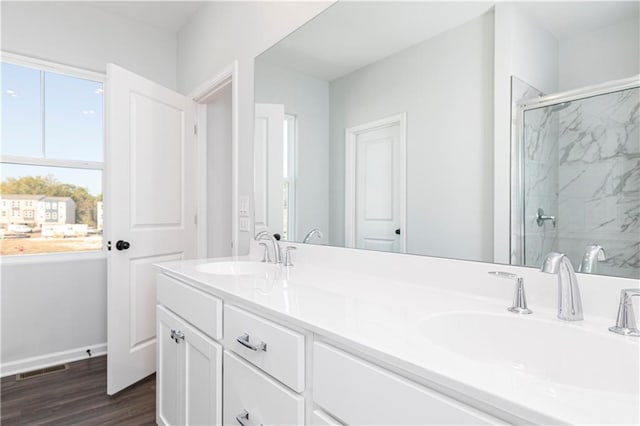 full bathroom with a shower stall, wood finished floors, and double vanity