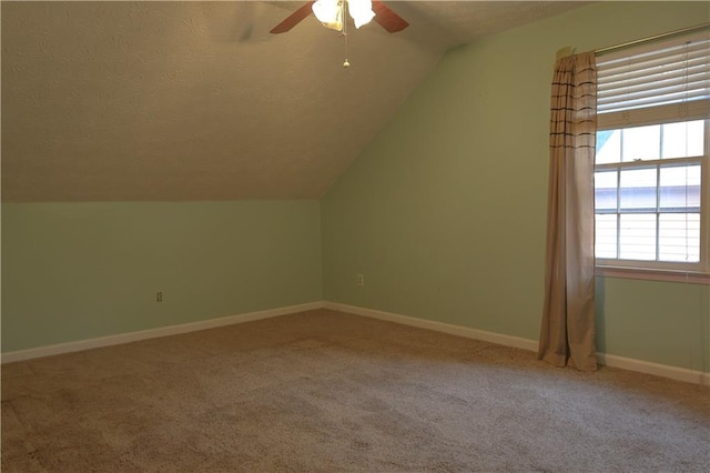 bonus room featuring a textured ceiling, carpet flooring, vaulted ceiling, and ceiling fan