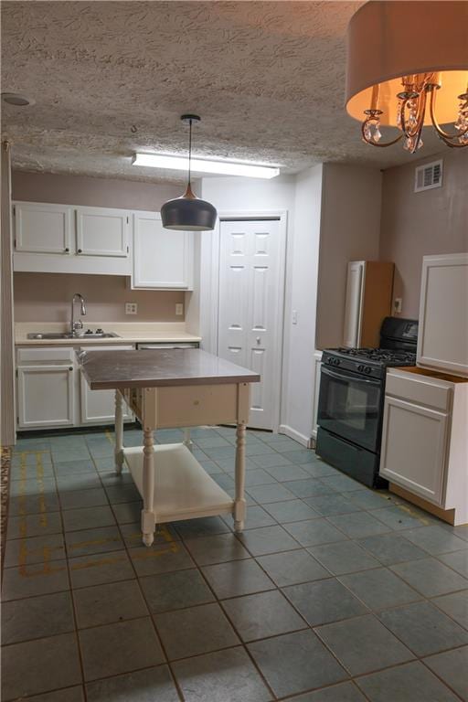 kitchen with white cabinetry, a chandelier, pendant lighting, and black gas range