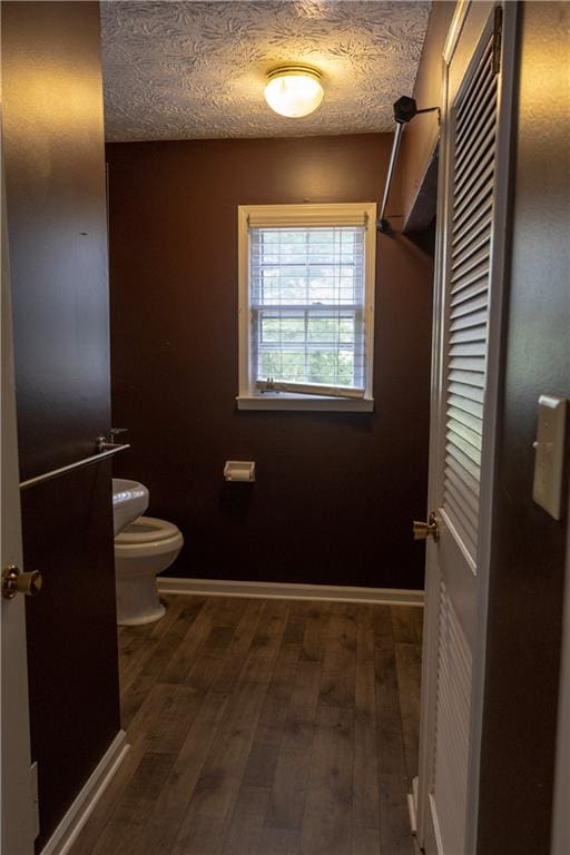 bathroom with a textured ceiling, hardwood / wood-style floors, and toilet