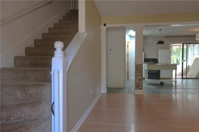 stairs with ornate columns and hardwood / wood-style floors