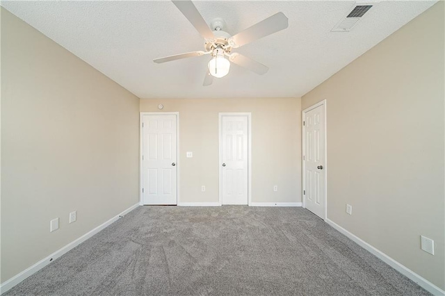 unfurnished bedroom featuring baseboards, visible vents, a ceiling fan, a textured ceiling, and carpet floors