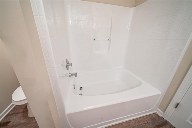 bathroom with baseboards, shower / tub combination, and toilet