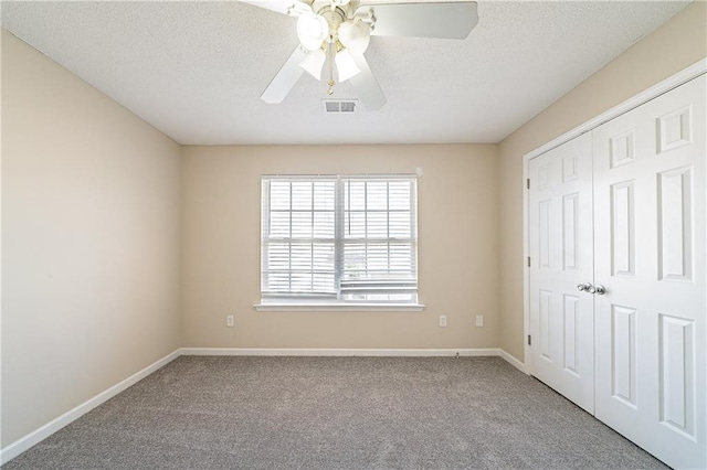 unfurnished bedroom with a textured ceiling, carpet flooring, visible vents, baseboards, and a closet