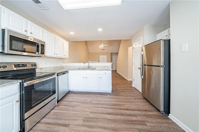 kitchen with visible vents, white cabinets, appliances with stainless steel finishes, a peninsula, and a sink