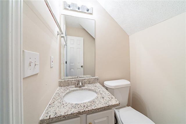 bathroom featuring lofted ceiling, vanity, toilet, and a textured ceiling