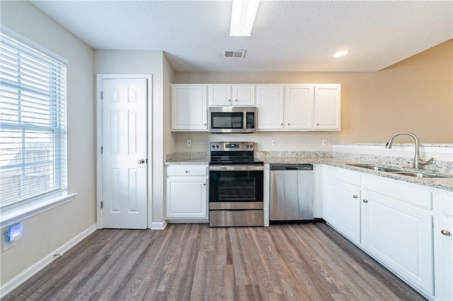 kitchen featuring wood finished floors, a sink, visible vents, white cabinetry, and appliances with stainless steel finishes