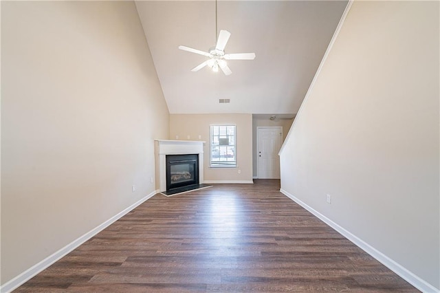 unfurnished living room with baseboards, dark wood finished floors, a glass covered fireplace, ceiling fan, and high vaulted ceiling