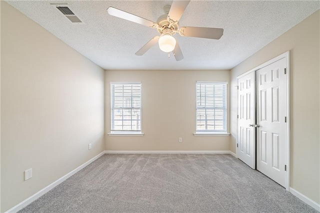 spare room with carpet floors, a wealth of natural light, visible vents, and baseboards