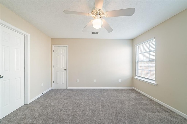 unfurnished room featuring a textured ceiling, carpet, visible vents, and baseboards