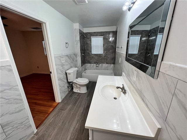 701 Cameron M Alexander Blvd NW, Atlanta, GA 30318 - bathroom with tile walls, vanity, toilet, bathtub / shower combination, and wainscoting