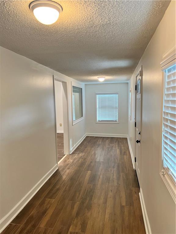 701 Cameron M Alexander Blvd NW, Atlanta, GA 30318 - spare room with a textured ceiling, dark wood-style floors, and baseboards