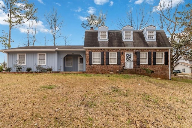 view of front of house featuring brick siding, board and batten siding, and a front yard