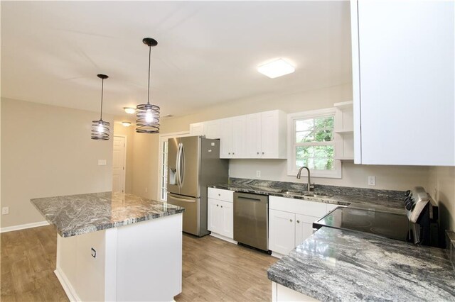 537 Eastside Dr, Dacula, GA 30019 - kitchen with stainless steel appliances, a sink, a center island, light wood finished floors, and white cabinetry