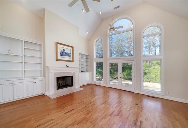unfurnished living room with a fireplace with flush hearth, visible vents, high vaulted ceiling, and ceiling fan