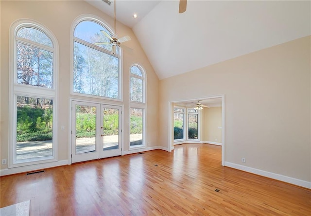 unfurnished living room featuring light wood-style flooring, visible vents, a ceiling fan, and high vaulted ceiling