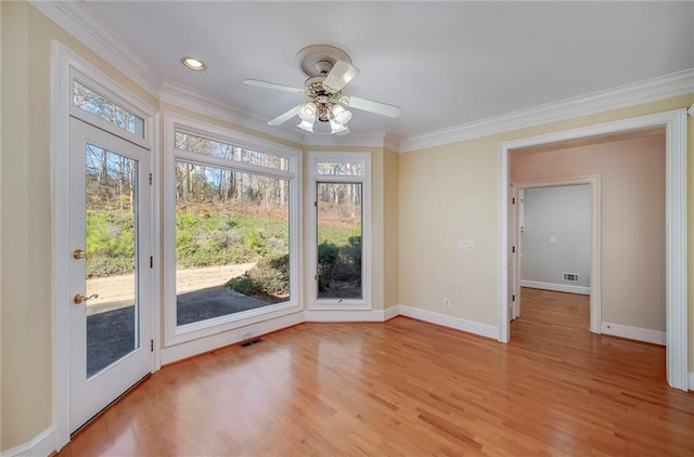 interior space with a ceiling fan, crown molding, light wood-style floors, baseboards, and visible vents