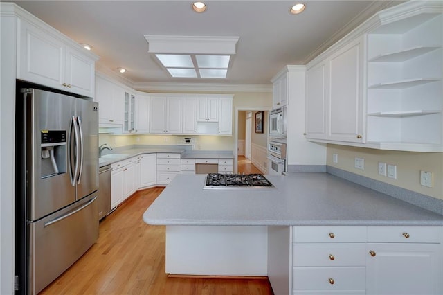 kitchen with white cabinets, a peninsula, appliances with stainless steel finishes, and light countertops