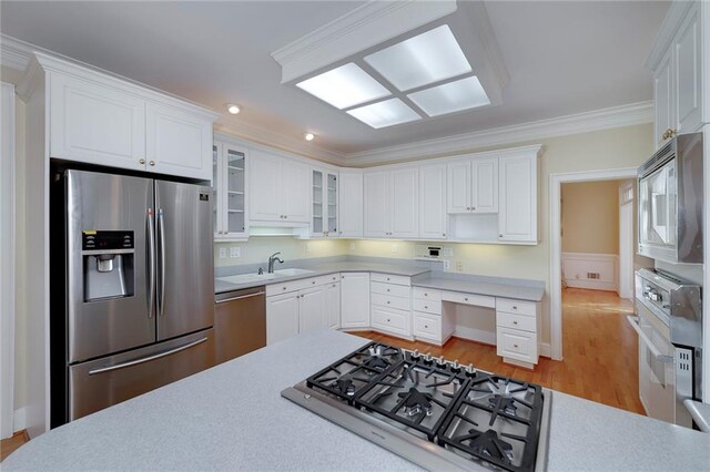 kitchen with white cabinets, light countertops, crown molding, glass insert cabinets, and appliances with stainless steel finishes