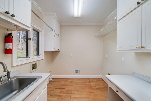 washroom with visible vents, a sink, light wood-type flooring, hookup for a washing machine, and cabinet space