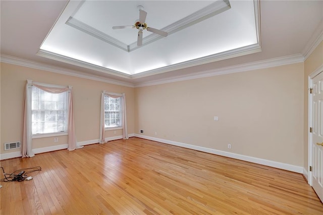 unfurnished room with a ceiling fan, light wood-style floors, baseboards, ornamental molding, and visible vents
