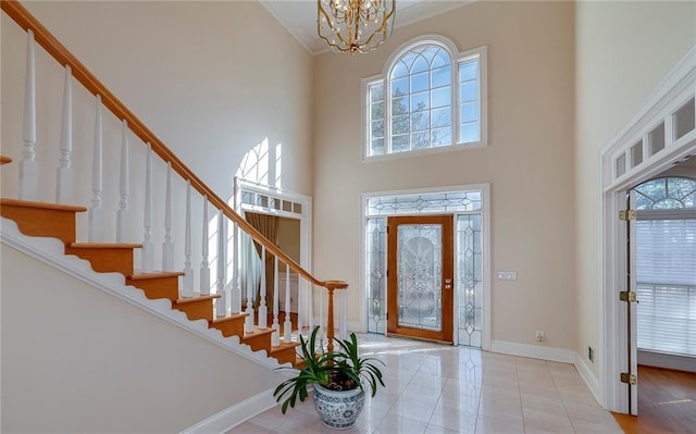tiled foyer entrance featuring stairway, ornamental molding, a notable chandelier, and plenty of natural light