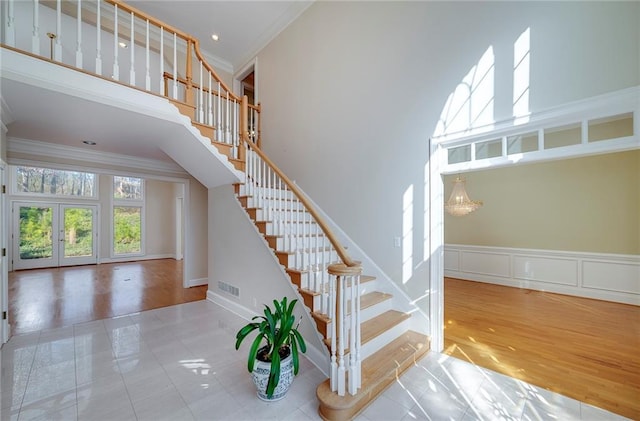 staircase featuring visible vents, french doors, a high ceiling, and ornamental molding