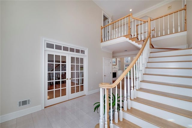 staircase with crown molding, french doors, a towering ceiling, baseboards, and visible vents