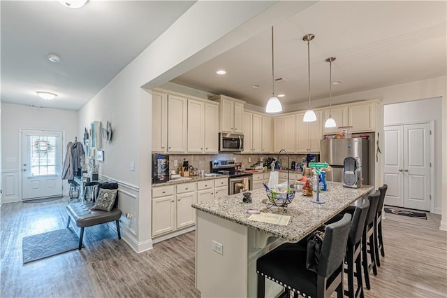 446 Vandenburg Dr, Villa Rica, GA 30180 - kitchen featuring stainless steel appliances, light wood-type flooring, a kitchen breakfast bar, light stone counters, and a kitchen island with sink