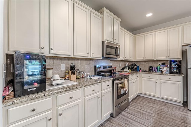 446 Vandenburg Dr, Villa Rica, GA 30180 - kitchen featuring stainless steel appliances, decorative backsplash, white cabinets, light stone countertops, and recessed lighting