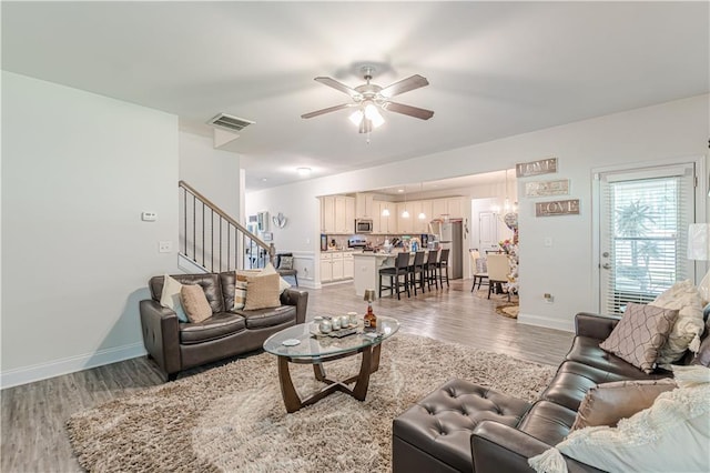 446 Vandenburg Dr, Villa Rica, GA 30180 - living area featuring light wood-type flooring, stairs, ceiling fan, baseboards, and a chandelier