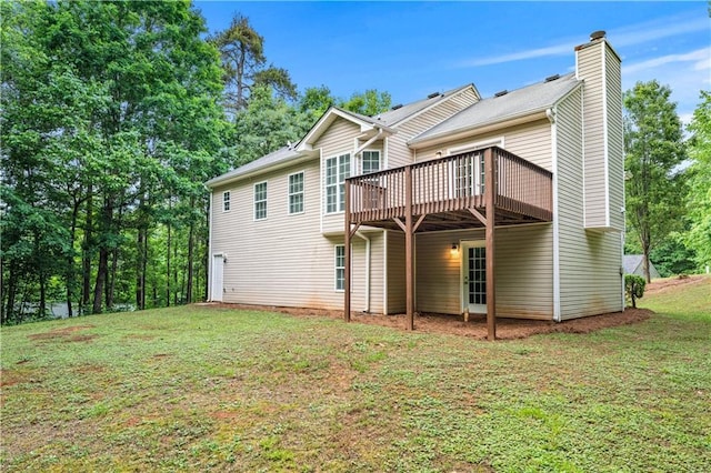 back of property with a chimney, a deck, and a lawn