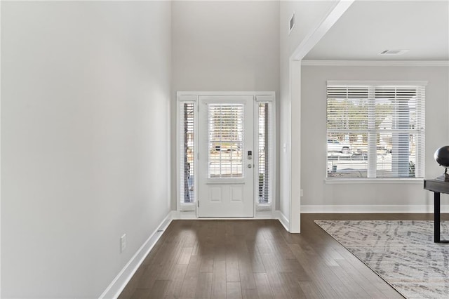 entrance foyer with ornamental molding, a wealth of natural light, and dark hardwood / wood-style flooring