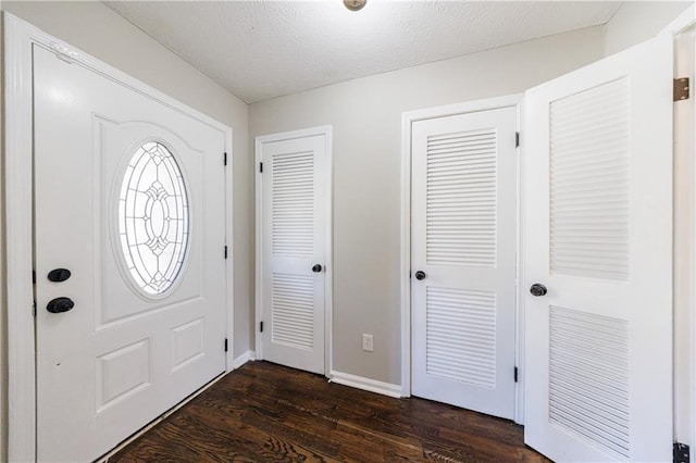 foyer with baseboards, a textured ceiling, and dark wood-style floors