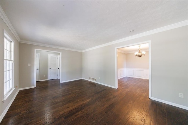 spare room featuring a wealth of natural light, dark wood-style floors, crown molding, and a notable chandelier