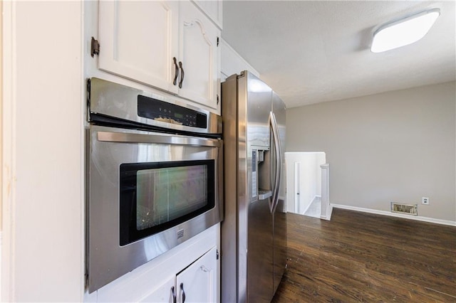 kitchen with dark wood-style floors, visible vents, appliances with stainless steel finishes, and white cabinetry