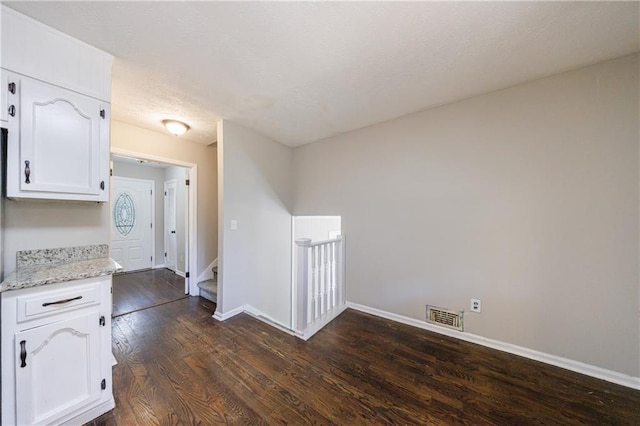 interior space featuring visible vents, baseboards, dark wood-style floors, and stairway