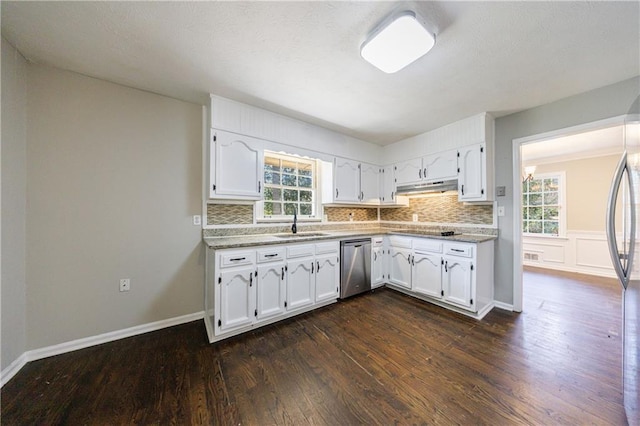 kitchen with under cabinet range hood, dishwasher, a sink, and white cabinetry