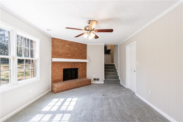 unfurnished living room with ornamental molding, a ceiling fan, stairway, carpet flooring, and a fireplace