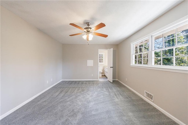 carpeted spare room featuring baseboards, visible vents, and ceiling fan