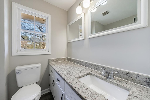 half bathroom with visible vents, toilet, vanity, and baseboards