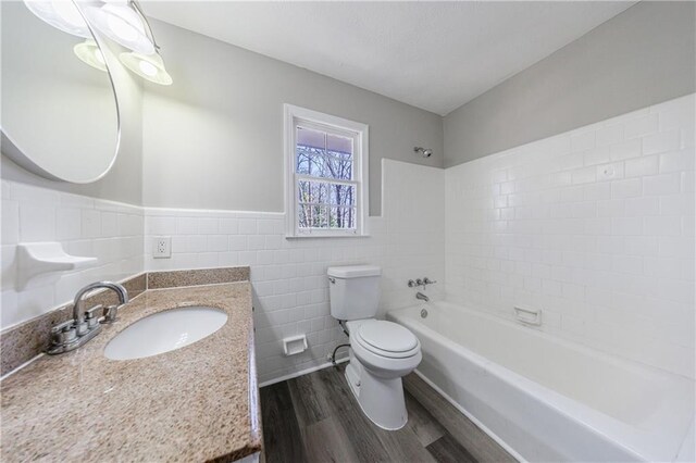 bathroom featuring toilet, shower / tub combination, wainscoting, wood finished floors, and tile walls