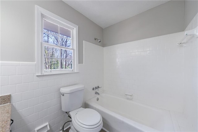 bathroom featuring  shower combination, toilet, tile walls, and wainscoting