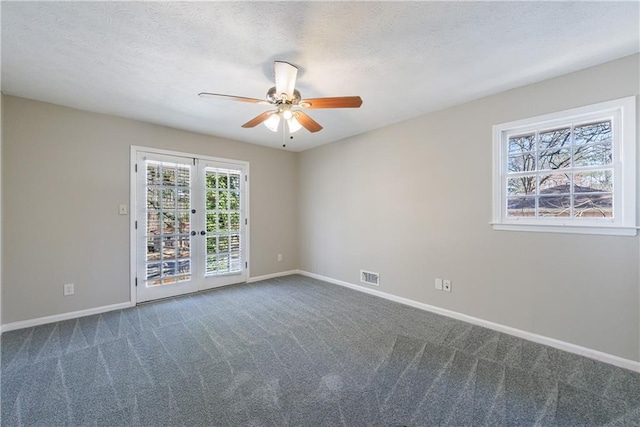 carpeted empty room with a ceiling fan, visible vents, baseboards, french doors, and a textured ceiling