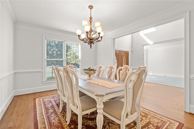 dining area with ornamental molding, an inviting chandelier, and light wood-type flooring