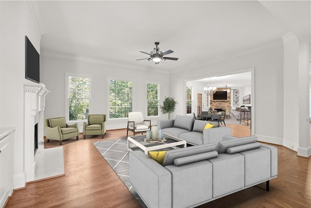 living room with ornamental molding, wood-type flooring, and ceiling fan with notable chandelier