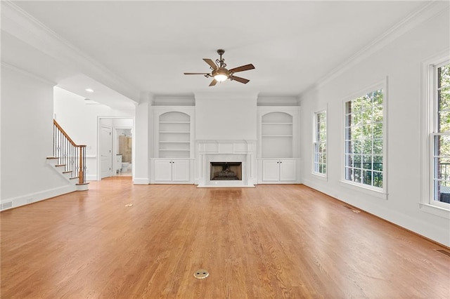 unfurnished living room featuring light hardwood / wood-style floors, crown molding, and a wealth of natural light