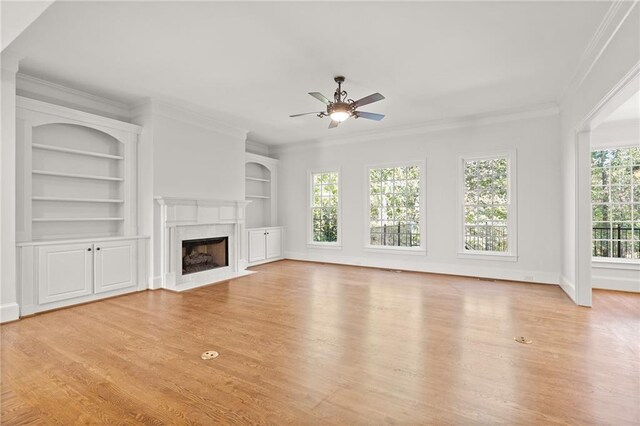 unfurnished living room featuring ornamental molding, a fireplace, light wood-type flooring, and ceiling fan